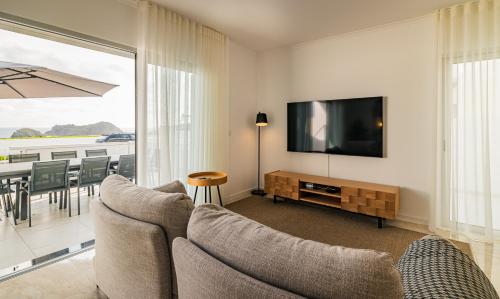 a living room with a television and a table with chairs at The Islet Retreat in Vila Franca do Campo