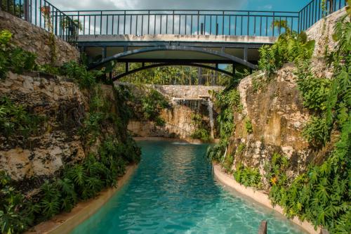 a bridge over a river with blue water at Hacienda Cenote San Ignacio in Chocholá