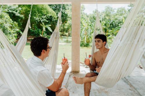 two men sitting in hammocks talking to each other at Hacienda Cenote San Ignacio in Chocholá