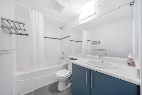 a white bathroom with a toilet and a sink at Beautiful Dt 3 Bed 2Bath Apat Free Parking & Pool in Vancouver