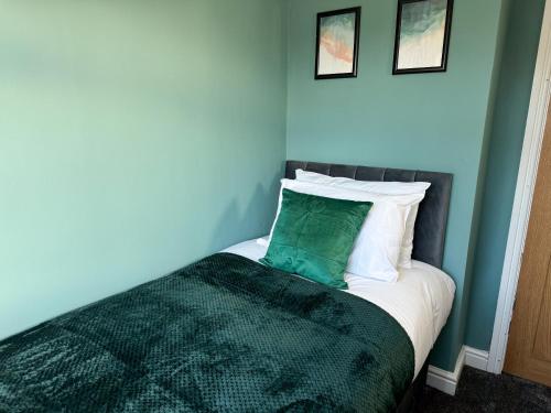 a bed with a green pillow on top of it at Stoneleigh Retreat 4BR Entire Home in Middlesbrough