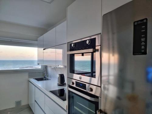une cuisine avec un micro-ondes et une cuisinière four supérieur dans l'établissement Departamento Pinterest Mar del Plata - Vista plena al mar con cochera, à Mar del Plata