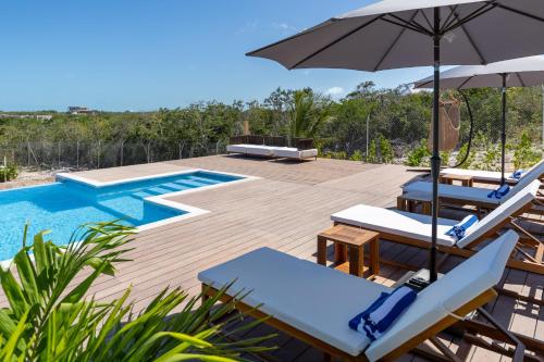 a swimming pool with lounge chairs and an umbrella at Sienna I Long Bay Retreat I Luxury Stay Near Grace Bay & Long Bay Beach in Long Bay Hills