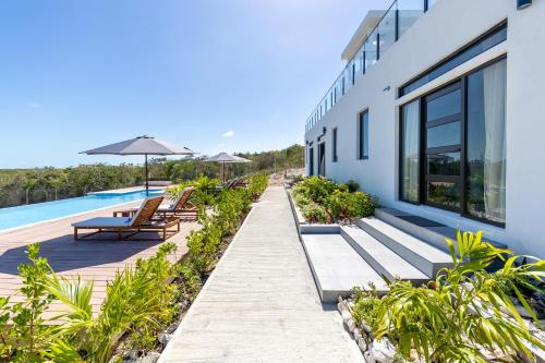 a resort with a pool and benches and an umbrella at Sienna I Long Bay Retreat I Luxury Stay Near Grace Bay & Long Bay Beach in Long Bay Hills