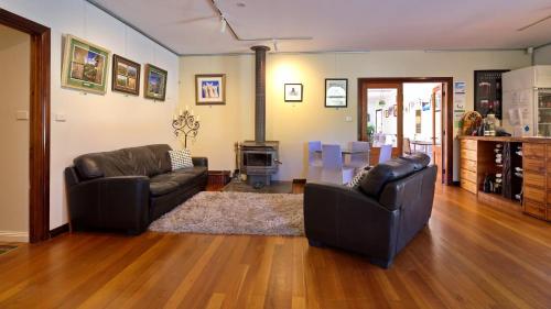 a living room with two leather couches and a kitchen at Tranquilles Bed & Breakfast in Port Sorell