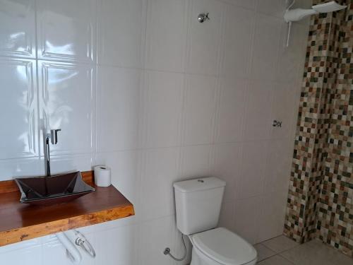 Un baño blanco con inodoro y lavabo. en Espaço Cris, en Pindamonhangaba