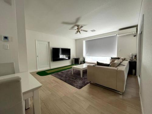 a living room with a couch and a tv at 帯広駅から車で10分 リバーサイドにある一軒をまるまる貸切12名まで in Otofuke