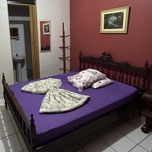 a bedroom with a bed with purple sheets and pillows at Pousada Orquidário in Santos