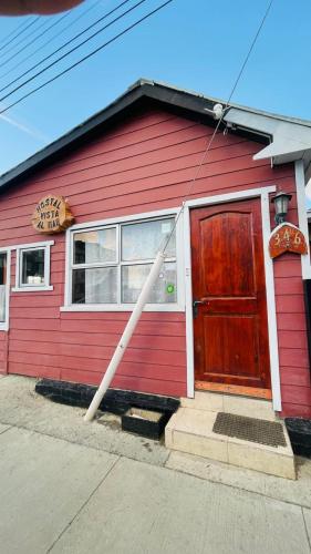 a red house with a red door and a sign at Hostal Vista al Mar in Puerto Natales