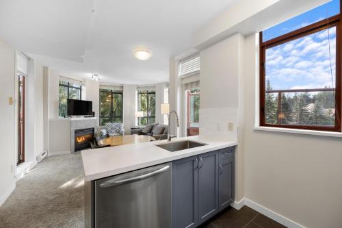 a kitchen with a sink and a fireplace at Alpenglow Lodge Two Bedroom Apartment with Private Hot Tub by MVA in Whistler