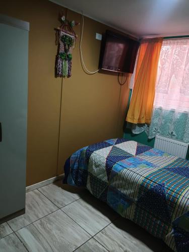 a bedroom with a bed and a tv on the wall at Hostal Vista al Mar in Puerto Natales