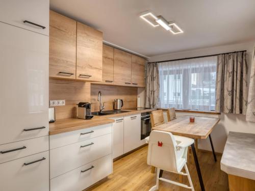 a kitchen with white cabinets and a wooden table at Chalet Bergglück in Sellrain