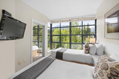 a bedroom with two beds and a flat screen tv at Alpenglow Lodge Two Bedroom Apartment by MVA in Whistler