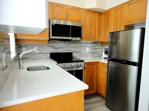 a kitchen with wooden cabinets and a stainless steel refrigerator at Alpenglow Lodge Two Bedroom Apartment by MVA in Whistler