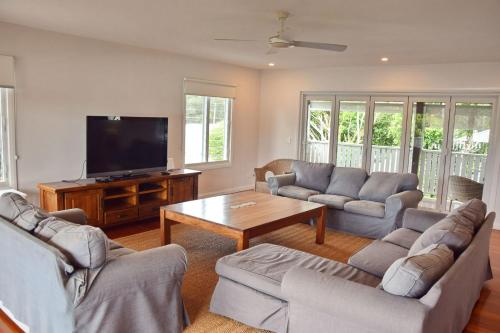 a living room with couches and a flat screen tv at Hat Head Holiday House - Bring your own linen in Hat Head