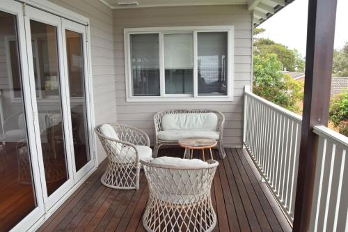 a porch with two wicker chairs and a table at Hat Head Holiday House - Bring your own linen in Hat Head