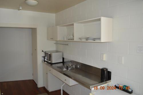a white kitchen with a sink and a microwave at Akaroa Village Inn in Akaroa