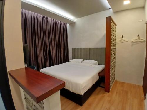a small bedroom with a bed and a wooden table at ParkCity Inn in Sibu