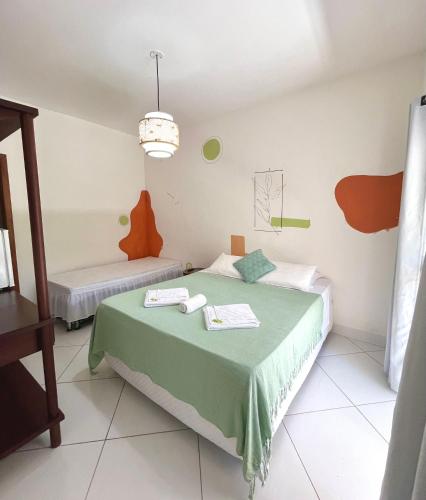 a bedroom with a bed with a green blanket at D'Ajuda Inn in Arraial d'Ajuda