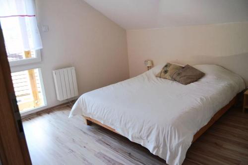 ein Schlafzimmer mit einem weißen Bett und einem Fenster in der Unterkunft Chalet Au Cottage des Lynx in Xonrupt-Longemer