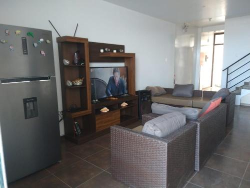 a living room with a couch and a refrigerator at Green Mare House in Zorritos
