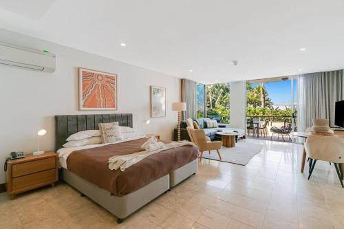 a bedroom with a large bed and a living room at 105 Santai - Ground Floor Studio Apartment by uHoliday in Casuarina