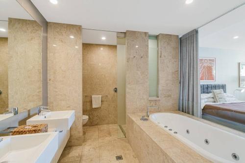 a bathroom with two sinks and a tub and a bed at 105 Santai - Ground Floor Studio Apartment by uHoliday in Casuarina