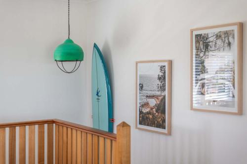 a hallway with two pictures and a surfboard on a wall at Sunset House - Oceanstays in Yamba