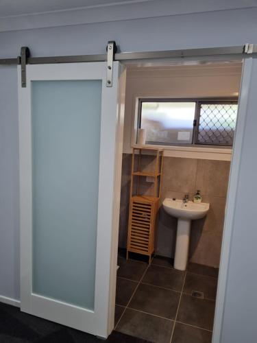 a bathroom with a door leading to a sink at Markwell Villa's Kingaroy in Kingaroy