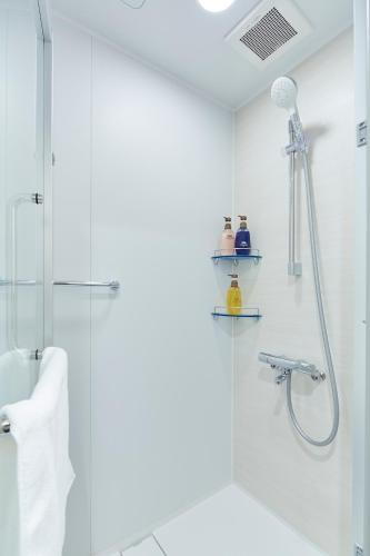 a white bathroom with a shower and a sink at hotel MONday Akihabara Asakusabashi in Tokyo