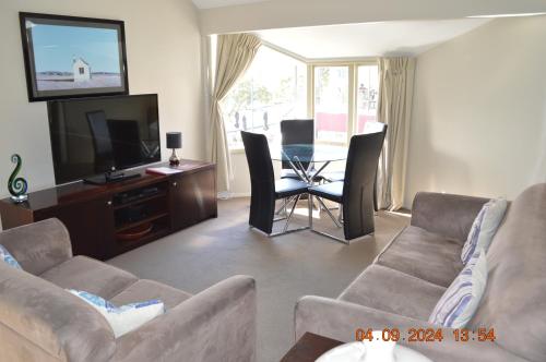 a living room with a couch and a tv and a table at Akaroa Village Inn in Akaroa