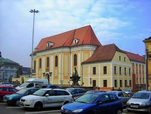 a large yellow building with a red roof and parked cars at Apartment Ztracená 8 in Olomouc