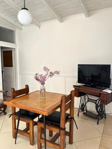 een eetkamer met een houten tafel en een televisie bij Departamento Céntrico 4 in El Bolsón