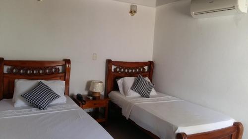 Habitación con 2 camas y mesa con lámpara. en Hotel Casa De España, en Mompox