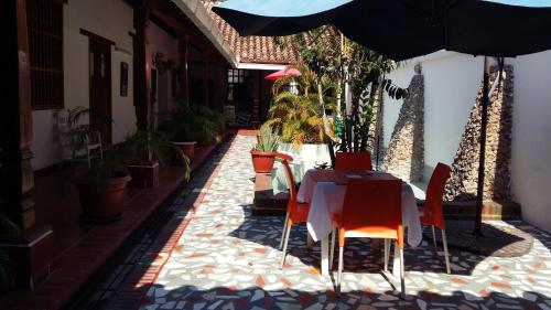 een tafel en stoelen met een parasol op een patio bij Hotel Casa De España in Mompos