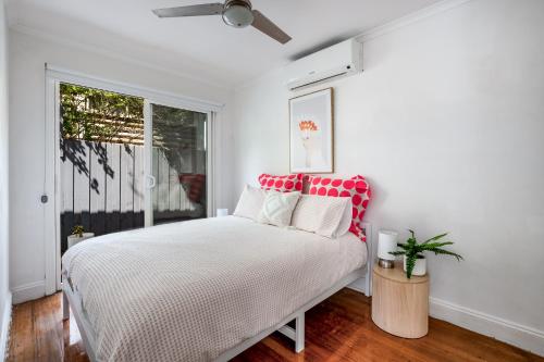 a white bedroom with a bed and a window at Orton Blue- Beachside getaway for 4, Pets welcome, Aircon, Park and walk to everything! in Ocean Grove
