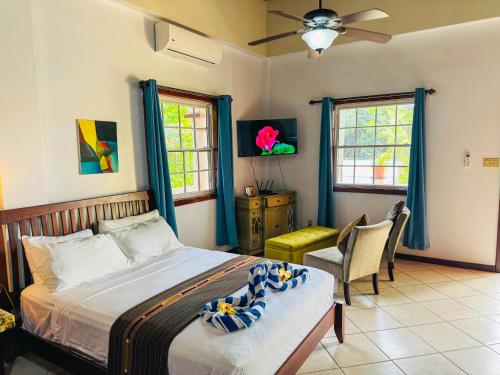 a bedroom with a bed and a desk and two windows at Caribbean Shores Belize in Hopkins