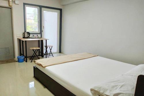 a white bedroom with a bed and a table at Na Nont Place in Bangkok