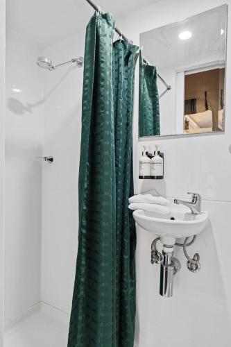 a bathroom with a green shower curtain and a sink at BIG4 Ingenia Holidays Inverloch in Inverloch