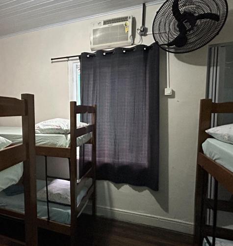 a room with two bunk beds and a fan at Pousada Orquidário in Santos