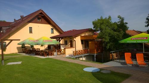 a house with chairs and umbrellas in a yard at Wellness Penzion Pod Rozhlednou in Kostelec nad Orlicí