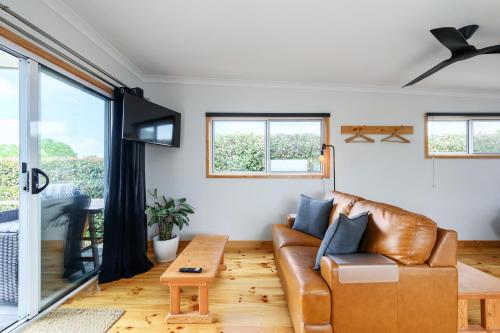 a living room with a leather couch and a table at Church Lane Accommodation, Milawa. in Milawa