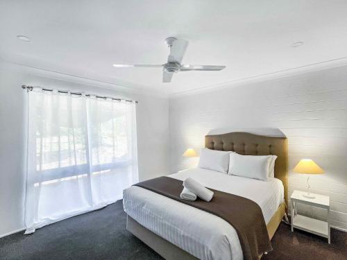 ein weißes Schlafzimmer mit einem großen Bett und einem Fenster in der Unterkunft Cuvee Cottage in Lovedale