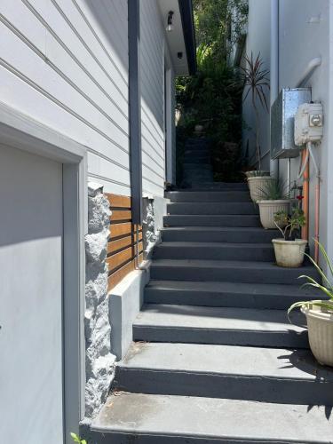 a staircase leading up to a house with potted plants at Cosy Cottage Above the Hawkesbury w/ Jetty in Mooney Mooney