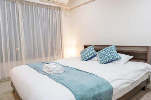 a bedroom with a bed with blue and white pillows at Pangoo Shinagawa in Tokyo