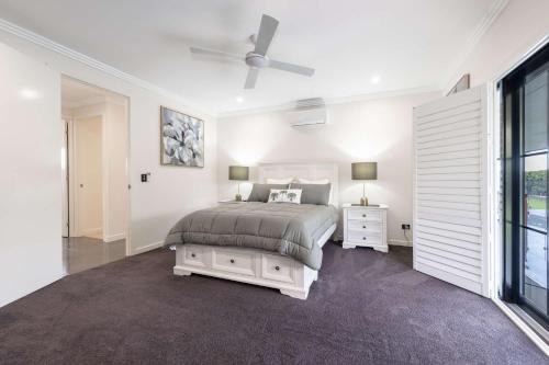 a white bedroom with a bed and a ceiling fan at Magic on MacArthur in Rosslea