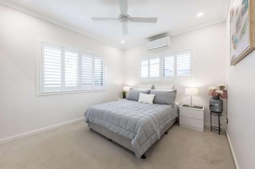 a white bedroom with a bed and two windows at Magic on MacArthur in Rosslea