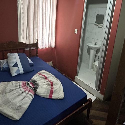 a bedroom with a bed and a bathroom with a sink at Pousada Orquidário in Santos