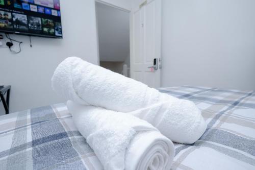 a pile of white towels sitting on a bed at Hope Deluxe King Bedroom Manchester in Middleton