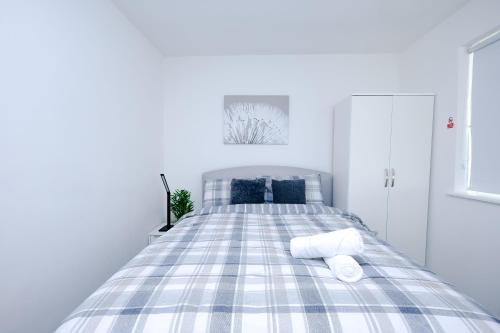 a bed with blue and white plaid sheets in a bedroom at Hope Deluxe King Bedroom Manchester in Middleton